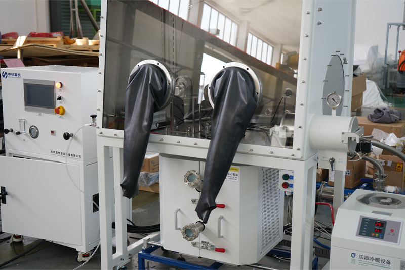 A CHJT laboratory glovebox with black rubber gloves, connected to an adjacent white control cabinet with a touchscreen interface. A CHJT laboratory glovebox with black rubber gloves, connected to an adjacent white control cabinet with a touchscreen interface.