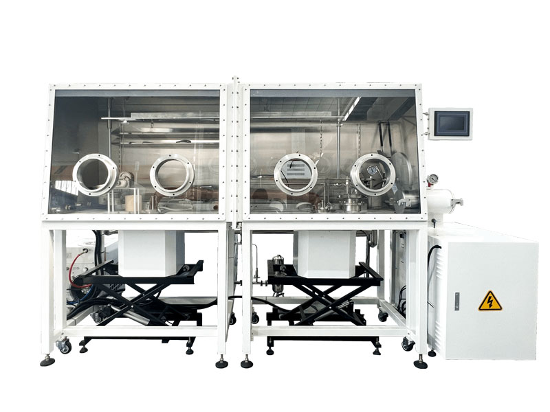 A dual-station inert atmosphere glovebox system on a mobile white frame. Each station features a stainless steel chamber with a clear front panel, and is positioned above a black scissor lift for material loading and unloading. The unit includes a touchscreen control panel and a main electrical cabinet. A dual-station inert atmosphere glovebox system on a mobile white frame. Each station features a stainless steel chamber with a clear front panel, and is positioned above a black scissor lift for material loading and unloading. The unit includes a touchscreen control panel and a main electrical cabinet.